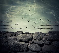 Stone wall fence of a prison with barbed metallic wire on top transform into flying birds over the lightning sky background