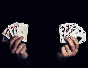 Caucasian male hands holding two royal flush poker combination of heart and spade