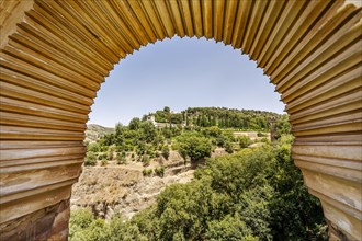 View of Generalife palace and garden through the Arabic arch in palace complex called Alhambra in Granada