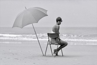 Woman with parasol on chair at the beach