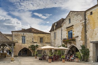 Old historic houses and a small restaurant with seats in front of it in the historic old town of Monpazier