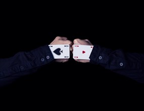 Two fists with hearts and spades aces against each other
