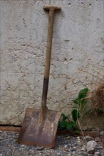 Old shovel leaning against house wall