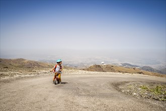 Small boy riding uphill on his first bicycle in Sierra Nevada mountains