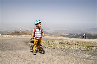 Small boy riding uphill on his first bicycle in Sierra Nevada mountains