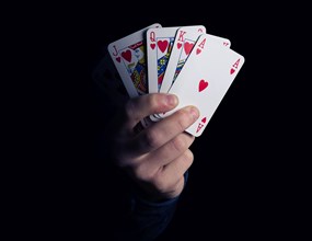 Hearts royal flush poker combination in man hand over black background