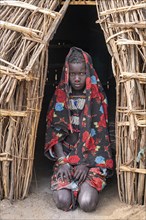 Traditional dressed child of the Jiye tribe sitting in her hut