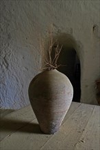 Old clay jug with bare branch in cave house