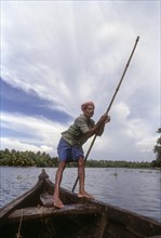 Boatman with a punt pole on a boat in the backwaters of Kerala