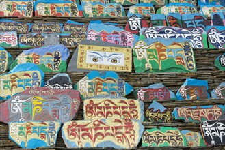 Huge piled up mountain of mani stones with Tibetan writing at a Tibetan monastery in the grasslands of Tagong