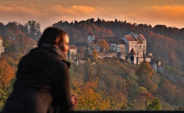 Young woman enjoying autumn evening light in front of Burghausen Castle