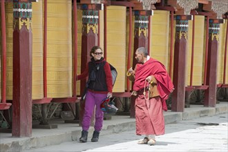 European young woman chatting with a Tibetan monk during the morning circumambulation