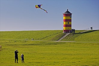 Girl flying a kite in front of the Pilsum lighthouse