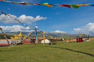 Golden roofs and chorten of a Tibetan monastery in the grassland of Tagong in front of Mount Zhara Lhatse