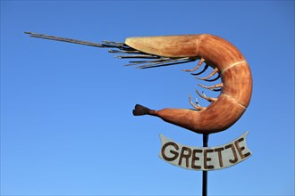 The sculpture of the North Sea crab Greetje at the fishing harbour against a blue sky
