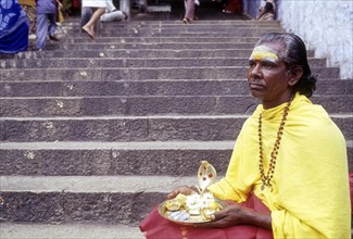 Elderly male Hindu beggar sitting on the steps of Dhandayuthapani temple at Palani near Coimbatore