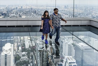 Tourists pose on the glass floor of Maha Nakhon Tower