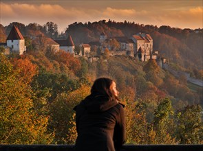Young woman enjoying autumn evening light in front of Burghausen Castle