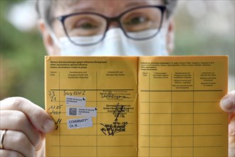 Woman proudly showing her vaccination certificate after third booster vaccination with BioNTec against Covid-19