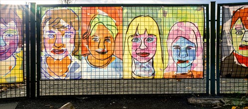 Colourful portraits attached to the fence of a Berlin school