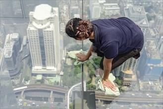 Woman cleaning glass floor of Maha Nakhon Tower