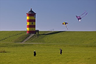 Girls flying kites in front of the Pilsum lighthouse