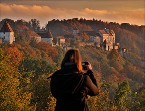 Young woman taking mobile phone photos of Burghausen Castle