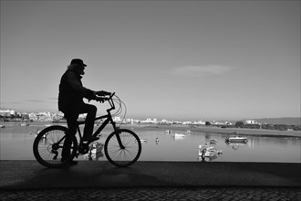 Silhouette of a cyclist in the harbour of Ferragudo