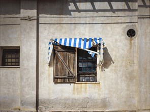 Window with broken awning on a residential house in Figari