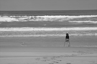 One-legged young woman on crutches by the sea