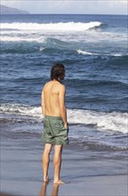 Young man standing in the sea on the beach of Praia de Santa Barbara
