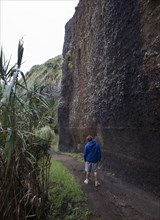 Hikers on the path to Rocha da Relva past eroded lava rocks