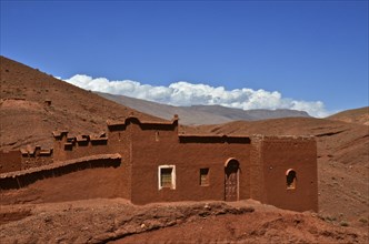 Red mud house with white clouds in mountains