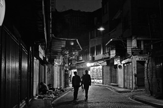 Two men walking through alley at night