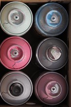 Six colourful spray cans in cardboard box