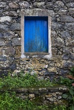 Residential house with stone facade and blue closed window in Rocha da Relva