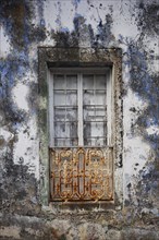 Weathered house facade with old closed window in Porto Formoso