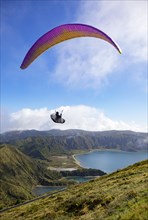 paraglider in flight over the crater lake Lagoa do Fogo