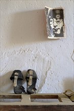 Old shoes70s newspaper page with John Lennon graphic on white wall