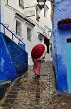Woman with red umbrella in alleys of Chefchaouen