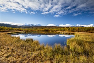 Mountain group Lapporten and snowy mountains of Abisko National Park reflected in small pond
