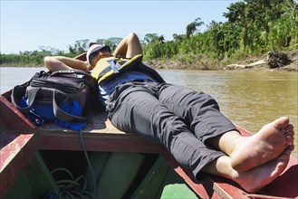 Tourist lying on the bow of a longboat