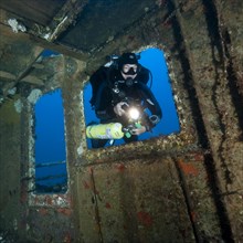 Diver views interior of shipwreck has special equipment for mixed gas diving