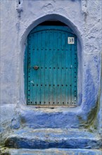 Mint-coloured entrance door with blue wall and house number 33