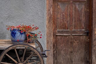 Still life with clay pot and wooden wagon in front of wooden door