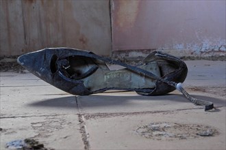 Black old broken lady's shoe lying on the floor