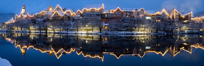Christmas illuminated house facade of Frohnleiten reflected in the river Mur