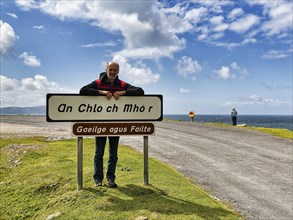 Tourist leaning against welcome sign in Irish