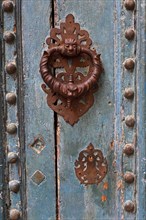 Ornate iron door knocker on mint green wooden door