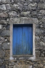 Residential house with stone facade and blue closed window in Rocha da Relva